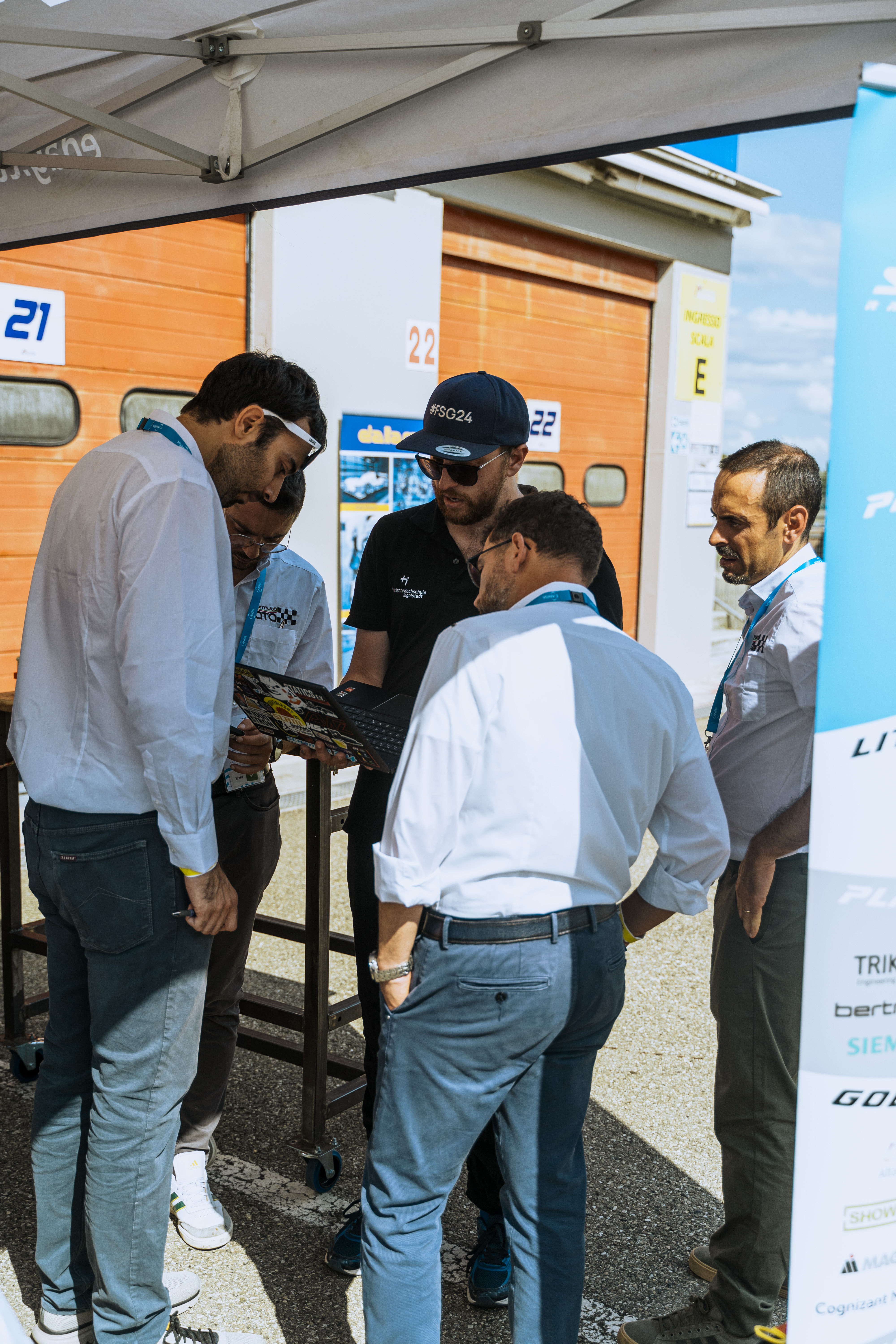 Technical judging discussion beside the Formula Student racecar at FS Italy 2025