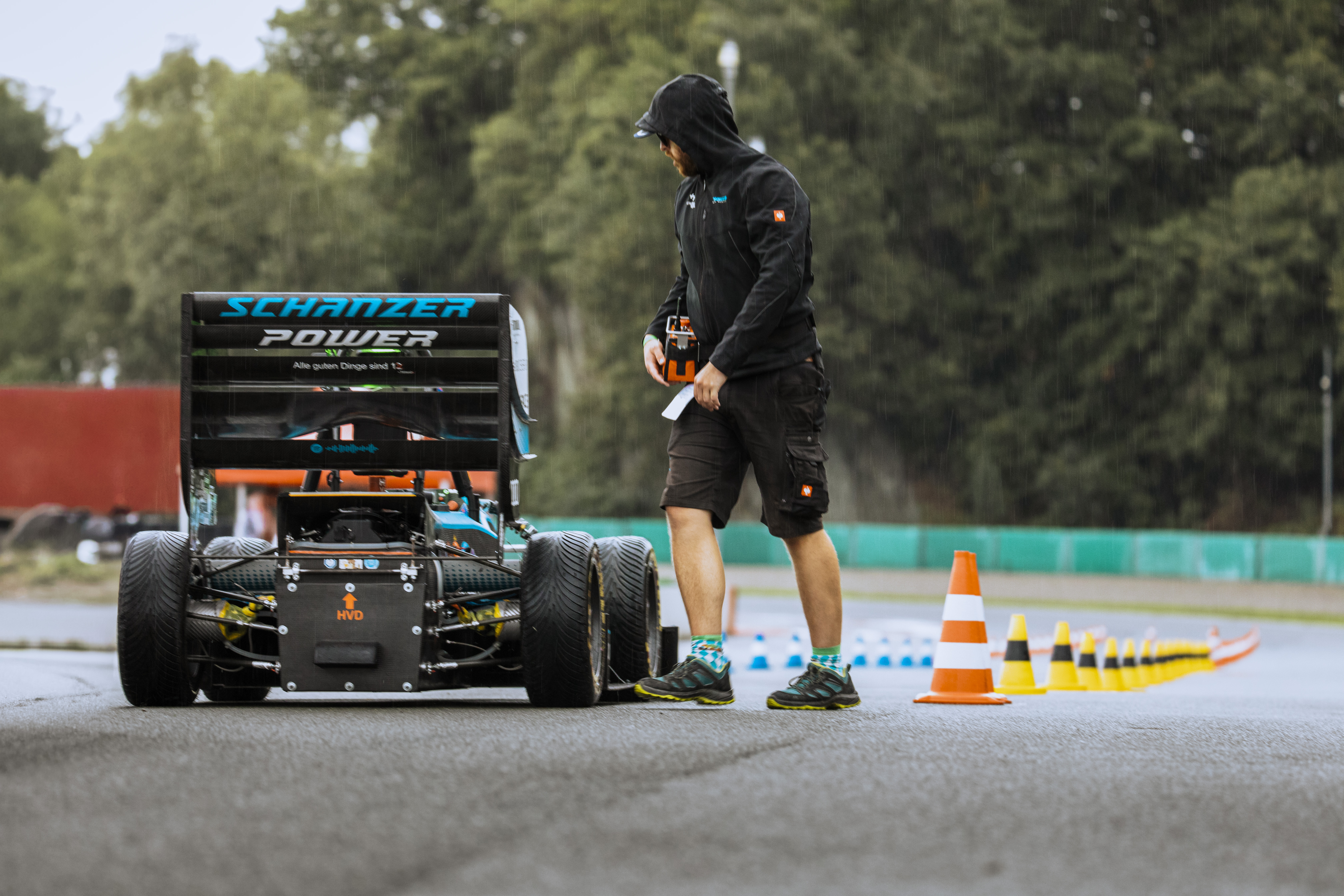 Team member beside the autonomous racecar during rainy EBS testing