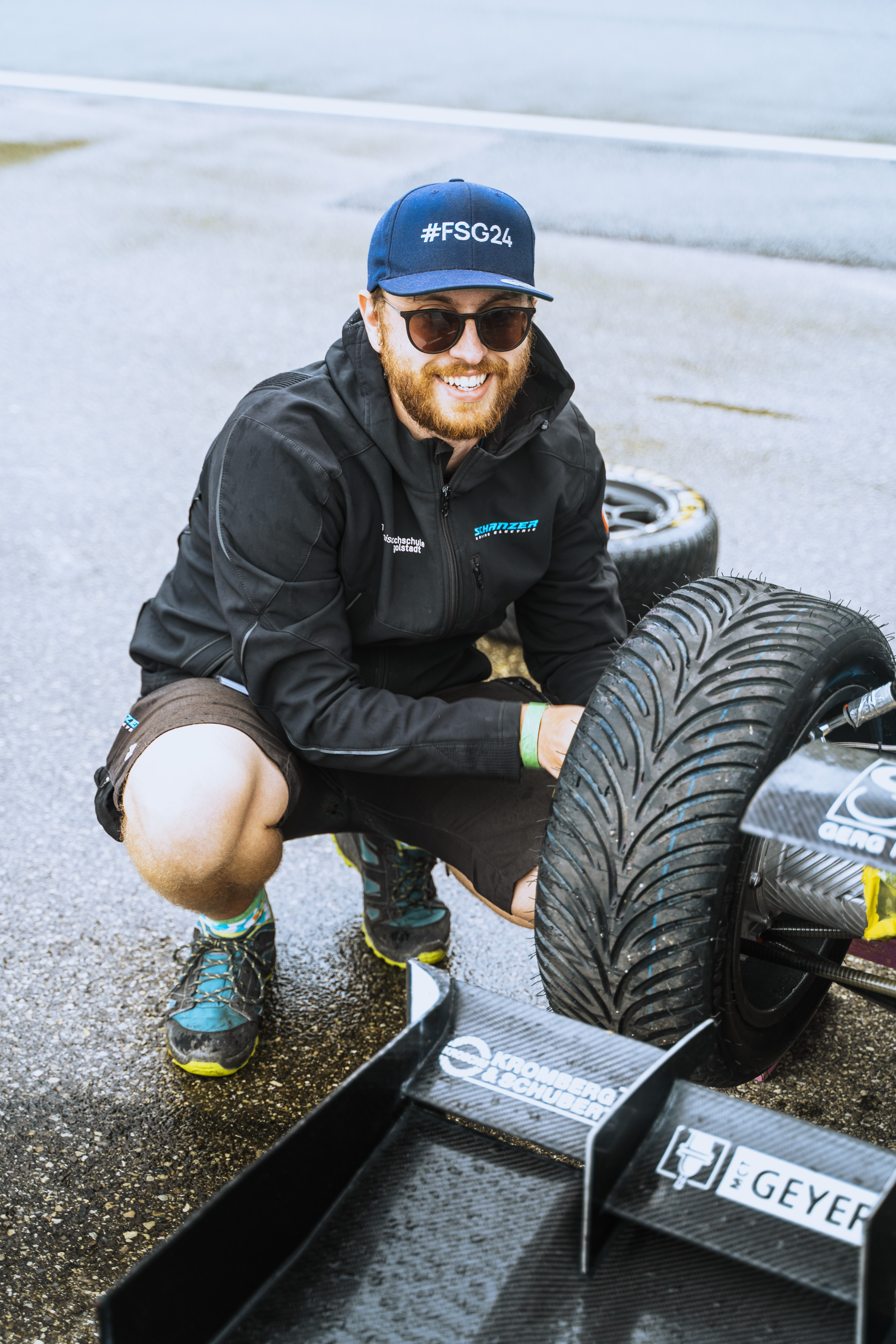 Team member working near the racecar tire at FS Italy 2025
